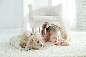 Child with labrador puppies at home on the carpet.