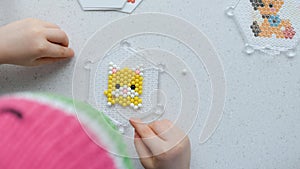 The child lays out an aqua mosaic in the form of a cat`s muzzle