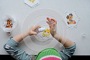 The child lays out an aqua mosaic in the form of a cat`s muzzle