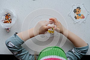 The child lays out an aqua mosaic in the form of a cat`s muzzle