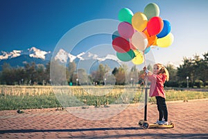 Child learn to ride kick scooter at park on summer