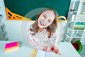 Child learning. Fun child girl in classroom near blackboard desk. School education and people concept - cute pupil over