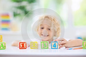 Child learning letters. Kid with wooden abc blocks