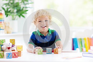 Child learning letters. Kid with wooden abc blocks