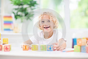 Child learning letters. Kid with wooden abc blocks