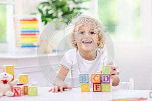 Child learning letters. Kid with wooden abc blocks