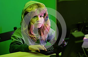 Child learning online at night, using desktop computer in living room at home. Child playing computer games or studying