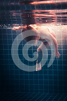 Child learning swimming underwater in swimming pool during diving training overcoming fear of deep