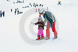The child learning to ski and man on the slope in