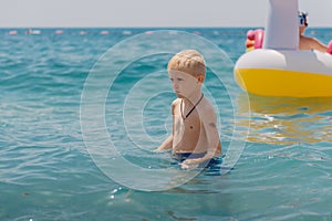 Child learning to swim in the open sea of tropical resort. Kids learn swimming. Exercise and training for young children