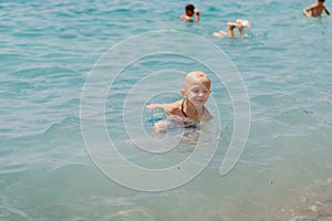 Child learning to swim in the open sea of tropical resort. Kids learn swimming. Exercise and training for young children