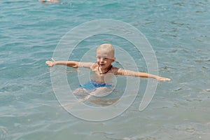 Child learning to swim in the open sea of tropical resort. Kids learn swimming. Exercise and training for young children