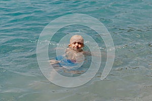Child learning to swim in the open sea of tropical resort. Kids learn swimming. Exercise and training for young children