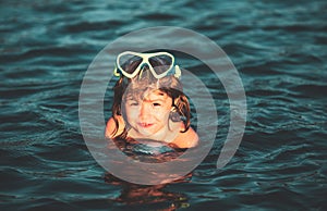 Child learning to swim in outdoor. Little kid boy at beach during summer vacation.