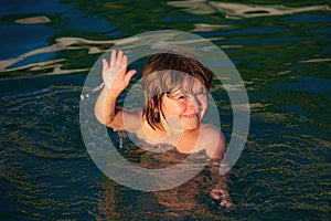 Child learning to swim in outdoor. Little kid boy at beach during summer vacation. Summer vacation and travel concept.