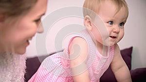 Child learning to walk with mother. Beautiful infant girl crawling at home