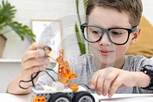 The child learns coding and programming and constructs a robot car, looks with concentration and fixes the control