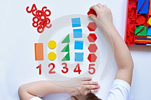 The child learns Number line and geometric shapes. The preschooler works with Montessori material photo