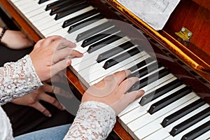 The child learns to play the piano under the guidance of a teacher.