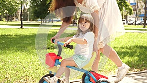 Child learns to ride bicycle. concept of happy family and childhood. parents and little daughter walks in park. Happy
