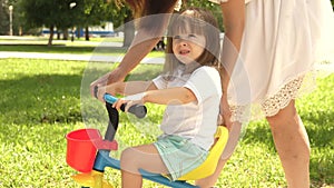 Child learns to ride bicycle. concept of happy family and childhood. parents and little daughter walks in park. Happy