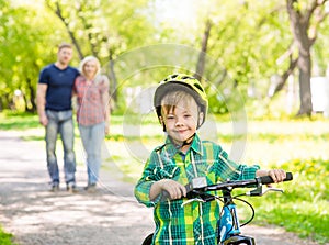The child learns to ride a bike with his parents in the park