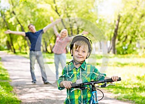 The child learns to ride a bike with his parents in the park