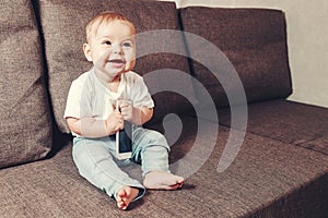 The child learns the world, modern children`s toys. Little smiling child sitting on the sofa bed with the phone in hand. copy spa