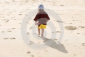 Child leaving small steps in the sand, playing barefoot