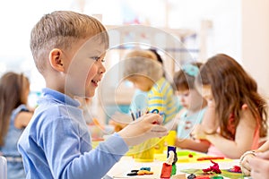 Child on lesson in classroom. Preschool kids group hands crafting in kindergarten