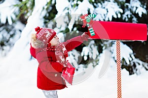 Child with letter to Santa at Christmas mail box in snow