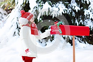 Child with letter to Santa at Christmas mail box in snow