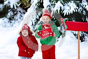 Child with letter to Santa at Christmas mail box in snow