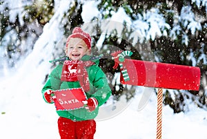 Child with letter to Santa at Christmas mail box in snow