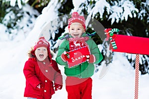 Child with letter to Santa at Christmas mail box in snow