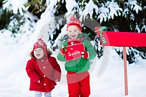 Child with letter to Santa at Christmas mail box in snow