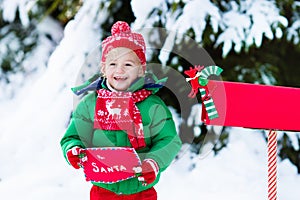 Child with letter to Santa at Christmas mail box in snow