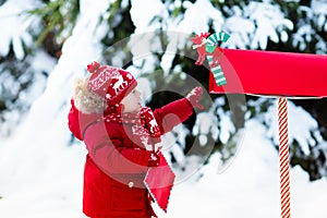 Child with letter to Santa at Christmas mail box in snow