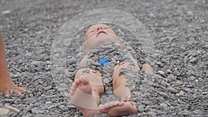 Child lies covered with pebbles.