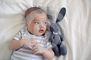 The child lies on his back on a big white bed