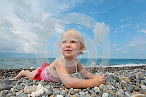 Child lies on pebble beach