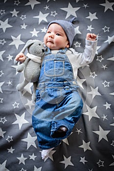 The child lies on a star blanket. Cute newborn baby girl lying in bed. Owl child sleeping on a blue blanket with stars. in