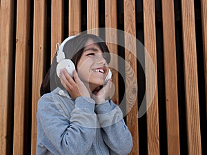 Child listening to music with white headphones.