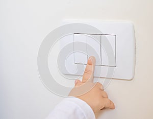 Child little boy turning on the white light-switch with his finger of little hand, new generation