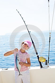 child little girl fishing in boat holding little tunny fish catch