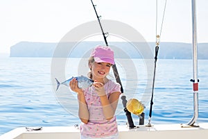 child little girl fishing in boat holding little tunny fish catch