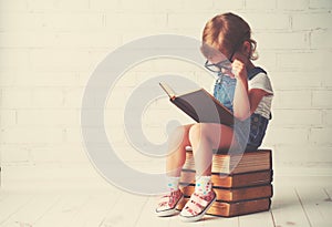 Child little girl with glasses reading a books