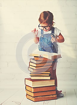 Child little girl with glasses reading a books