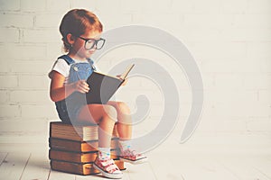 Child little girl with glasses reading a books