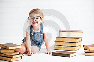 Child little girl with glasses reading a books